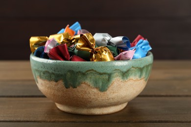 Candies in colorful wrappers on wooden table, closeup