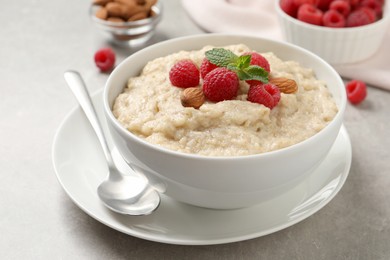 Photo of Tasty oatmeal porridge with raspberries and almond nuts served on light table