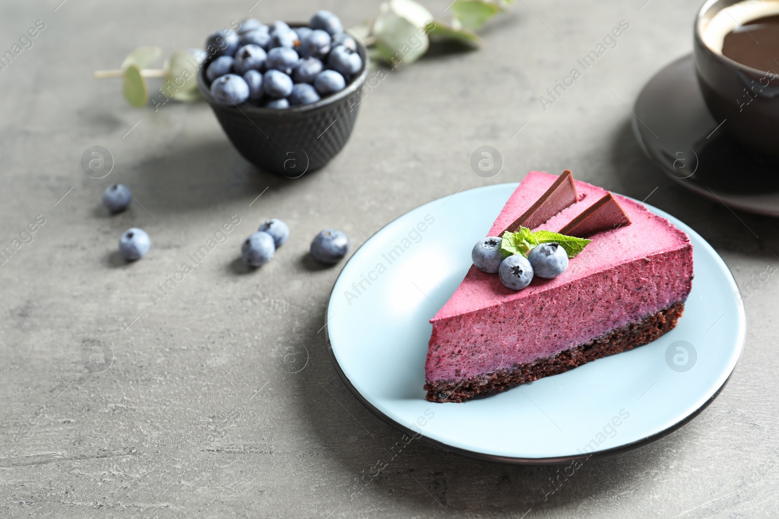 Photo of Plate with piece of tasty blueberry cake on gray table