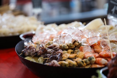 Delicious seafood skewers served in dish on table, closeup