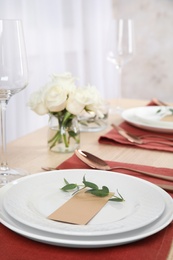 Elegant festive table setting with blank card in restaurant