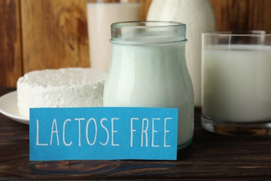 Photo of Card with phrase Lactose free and different fresh products on wooden table, closeup