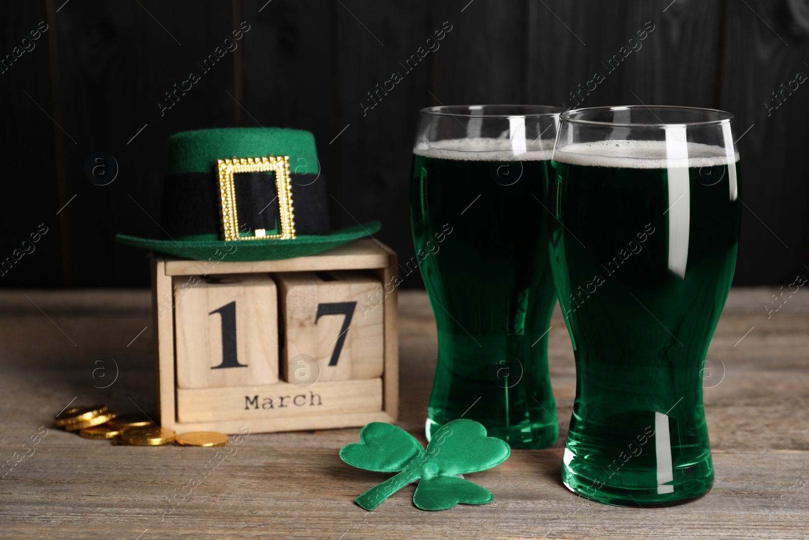 Photo of St. Patrick's day celebrating on March 17. Green beer, block calendar, leprechaun hat, gold coins and decorative clover leaf on wooden table