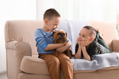 Photo of Portrait of cute boys with funny Brussels Griffon dog at home. Loyal friends