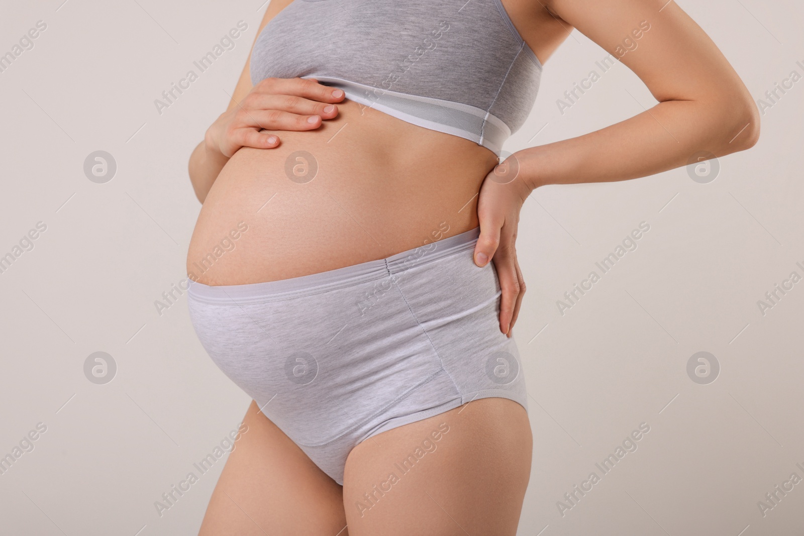 Photo of Pregnant woman in comfortable maternity underwear on grey background, closeup