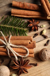 Different aromatic spices and fir branch on wooden table, above view