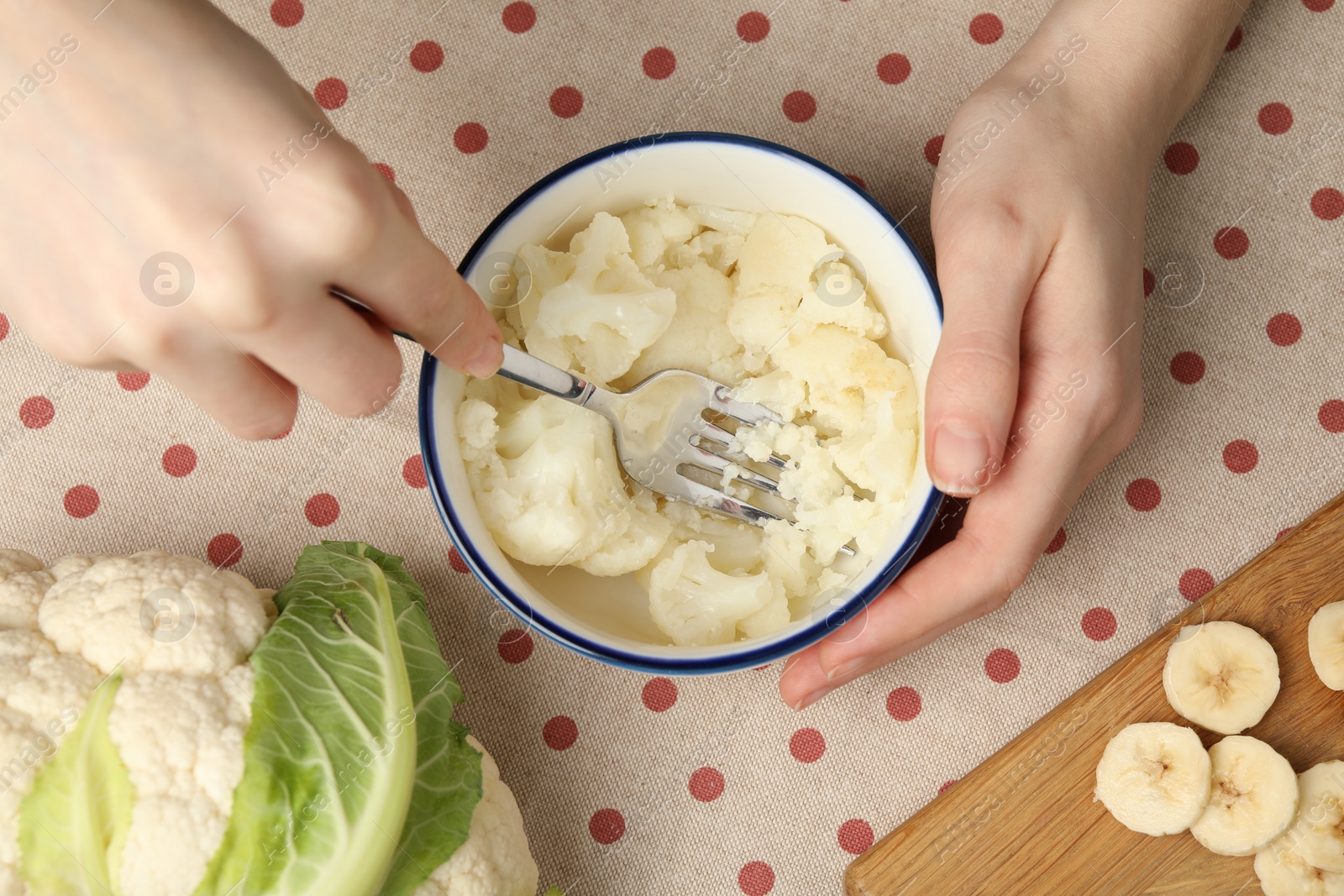 Photo of Woman making baby food with cauliflower at table, top view