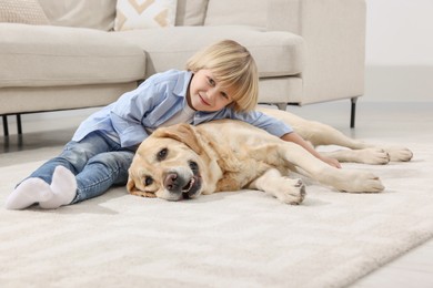 Cute little child with Golden Retriever on floor at home. Adorable pet