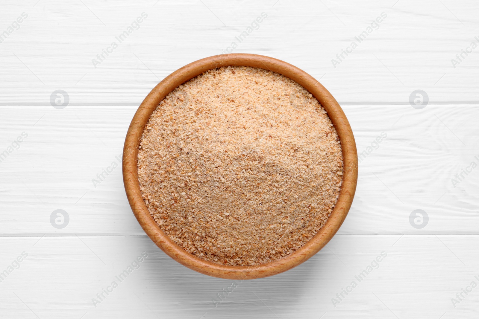 Photo of Fresh breadcrumbs in bowl on white wooden table, top view