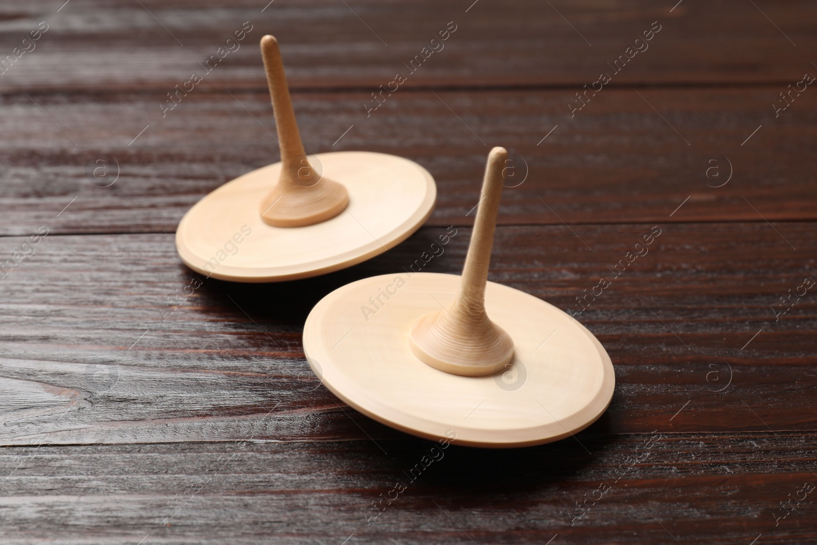 Photo of Two spinning tops on wooden table, closeup