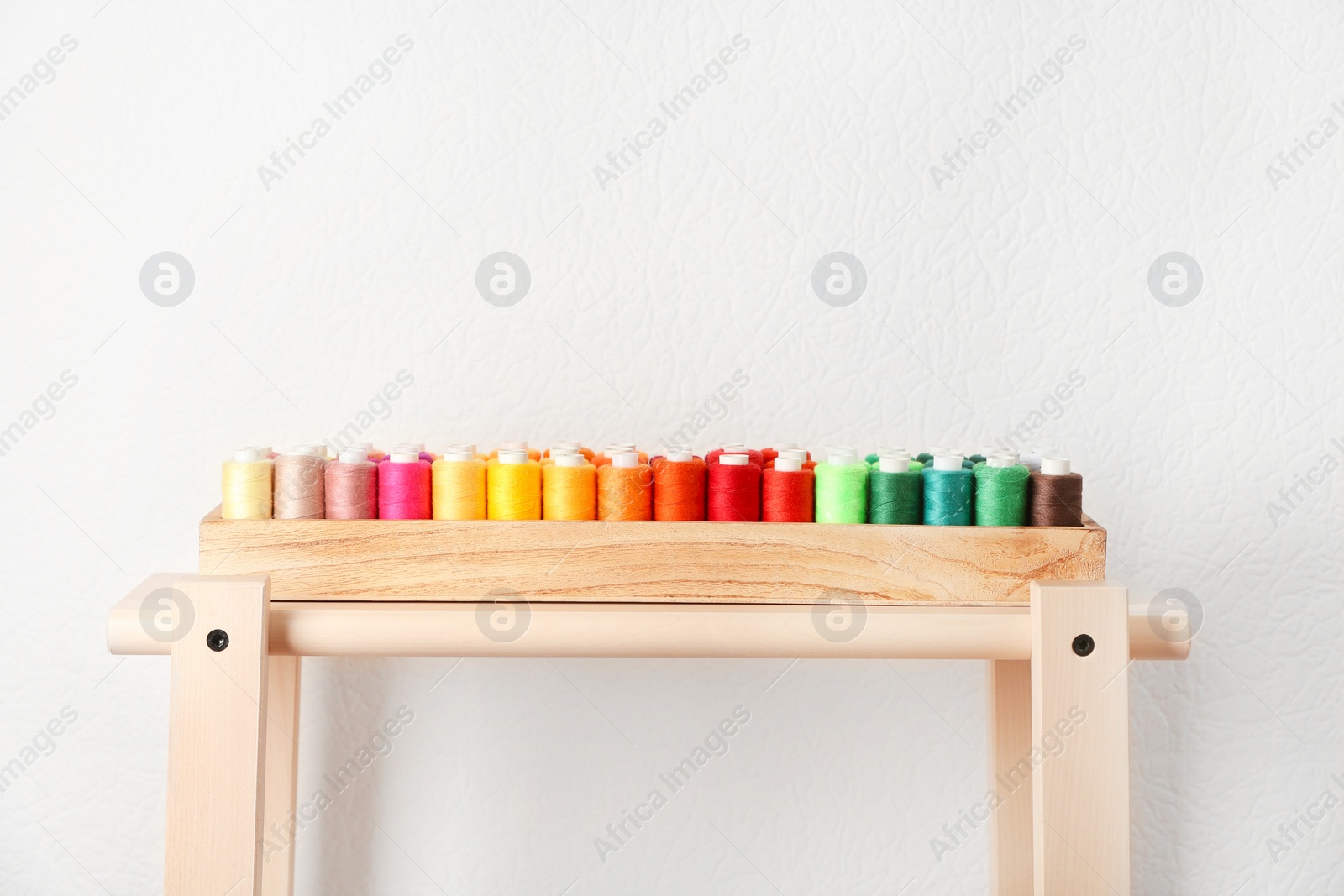 Photo of Wooden box with color sewing threads on table