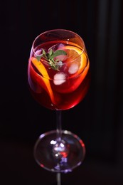 Photo of Glass of delicious refreshing sangria on black table