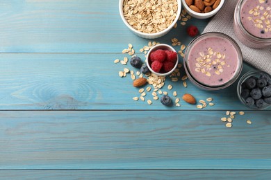 Photo of Tasty berry smoothie with oatmeal on light blue wooden table, flat lay. Space for text