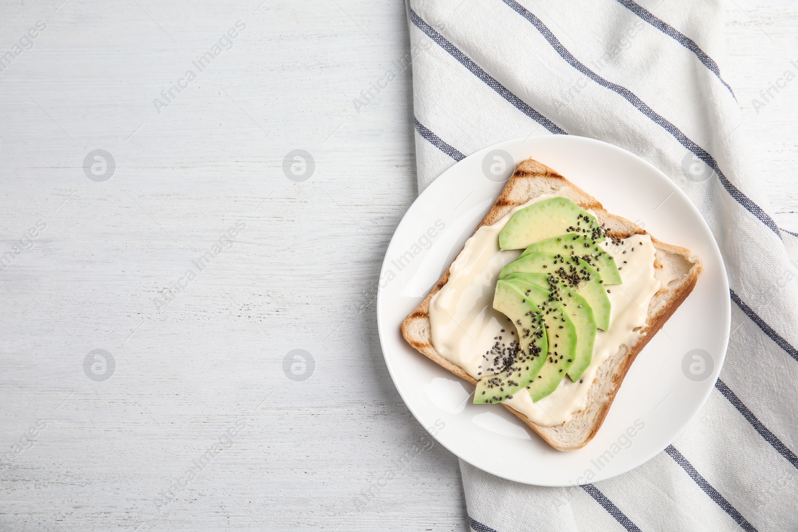 Photo of Slice of bread with spread and avocado on white wooden table, flat lay. Space for text