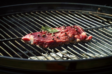 Photo of Tasty steak with pepper and rosemary on barbecue grill