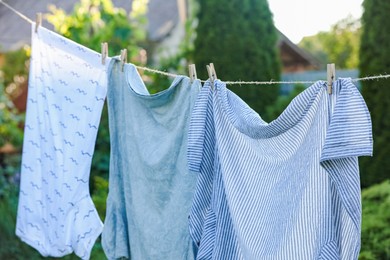Photo of Shirts drying on washing line outdoors. Clean clothes