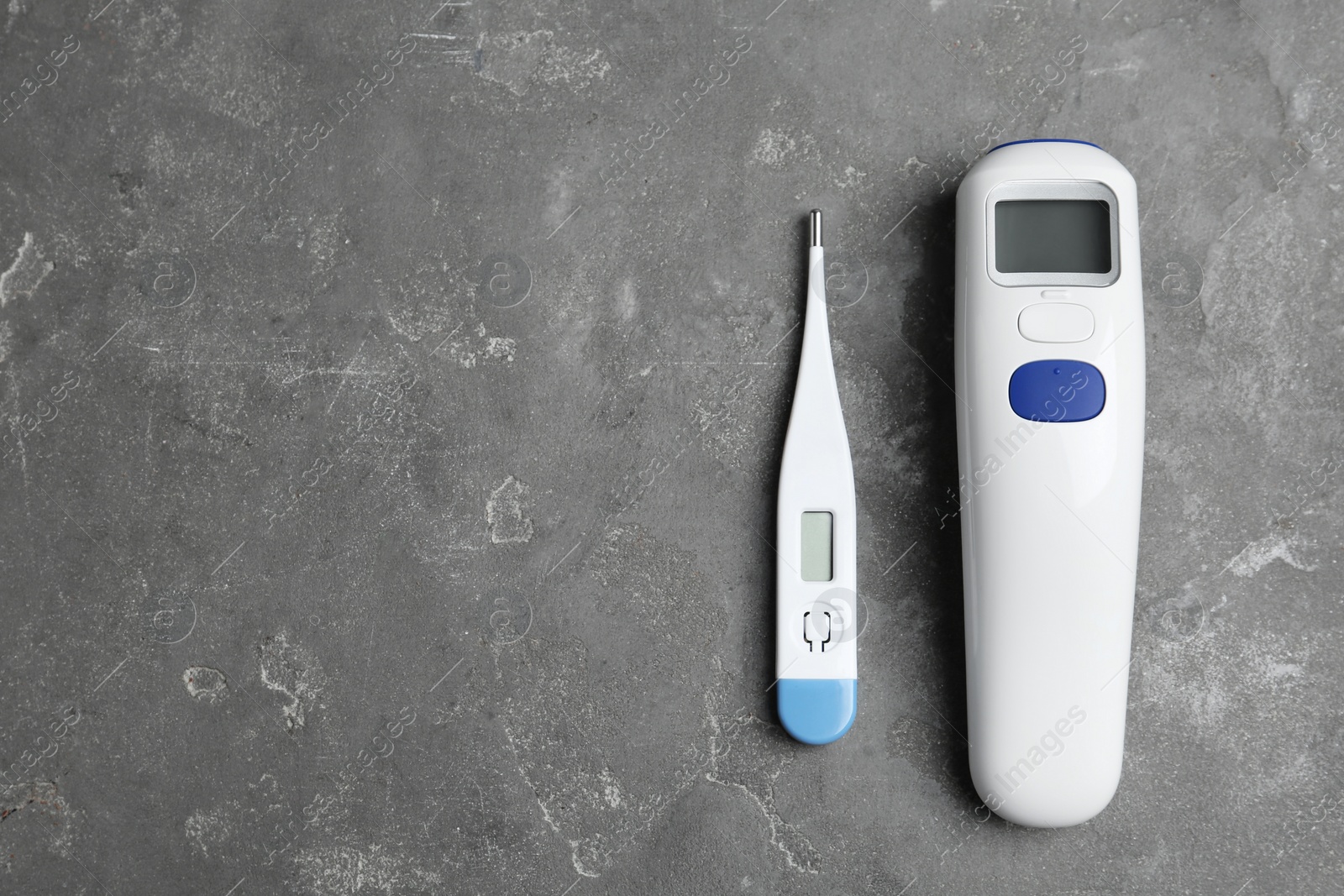 Photo of Non-contact infrared and digital thermometers on grey stone background, flat lay. Space for text