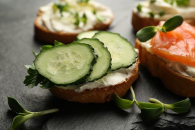 Photo of Delicious sandwiches with cream cheese and other ingredients on black table, closeup