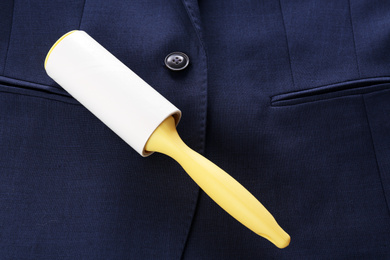 Photo of New lint roller with yellow handle on blue jacket, top view