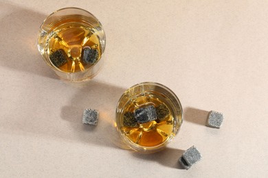 Photo of Whiskey stones and drink in glasses on light table, top view