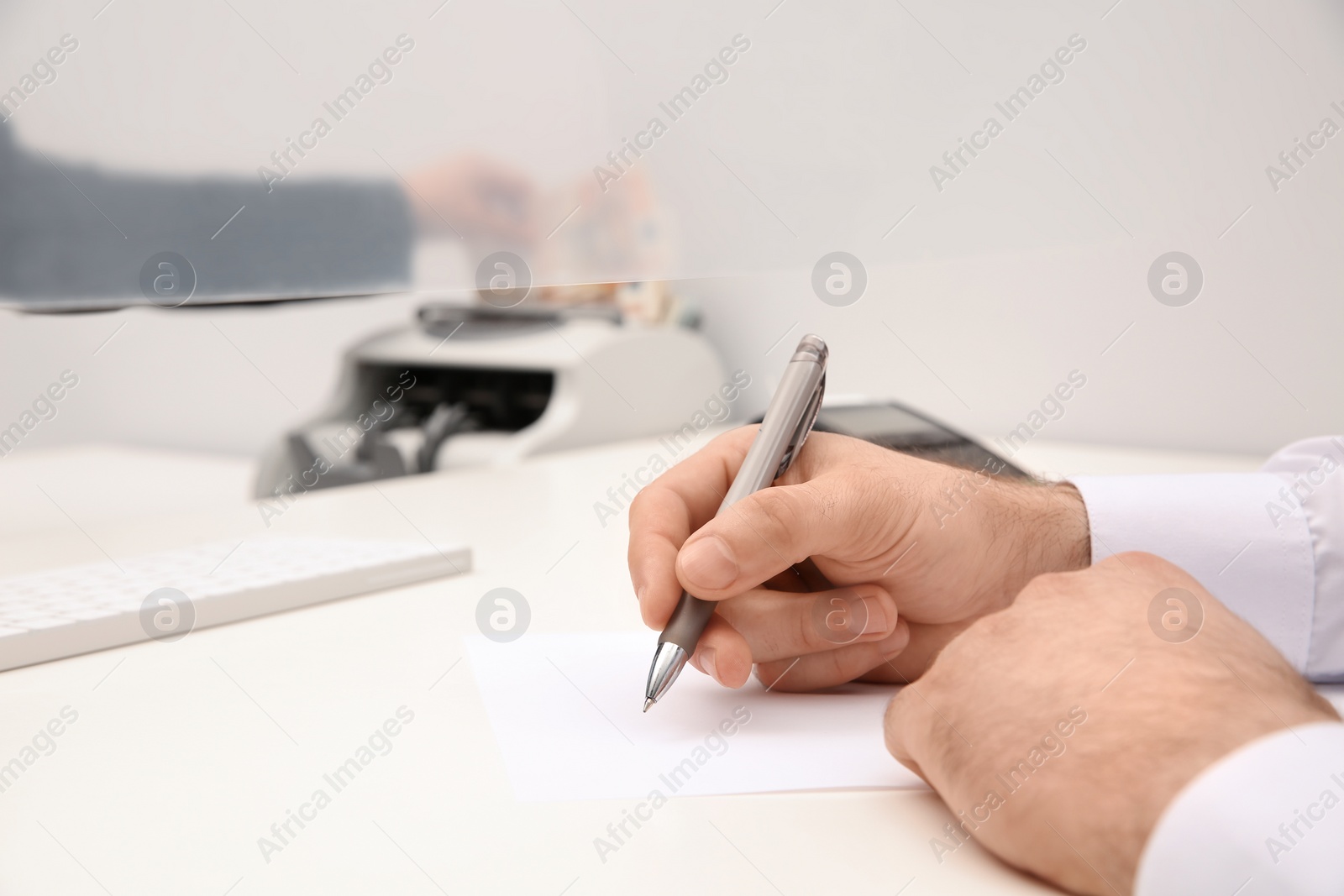 Photo of Man filling blank at cash department window, closeup