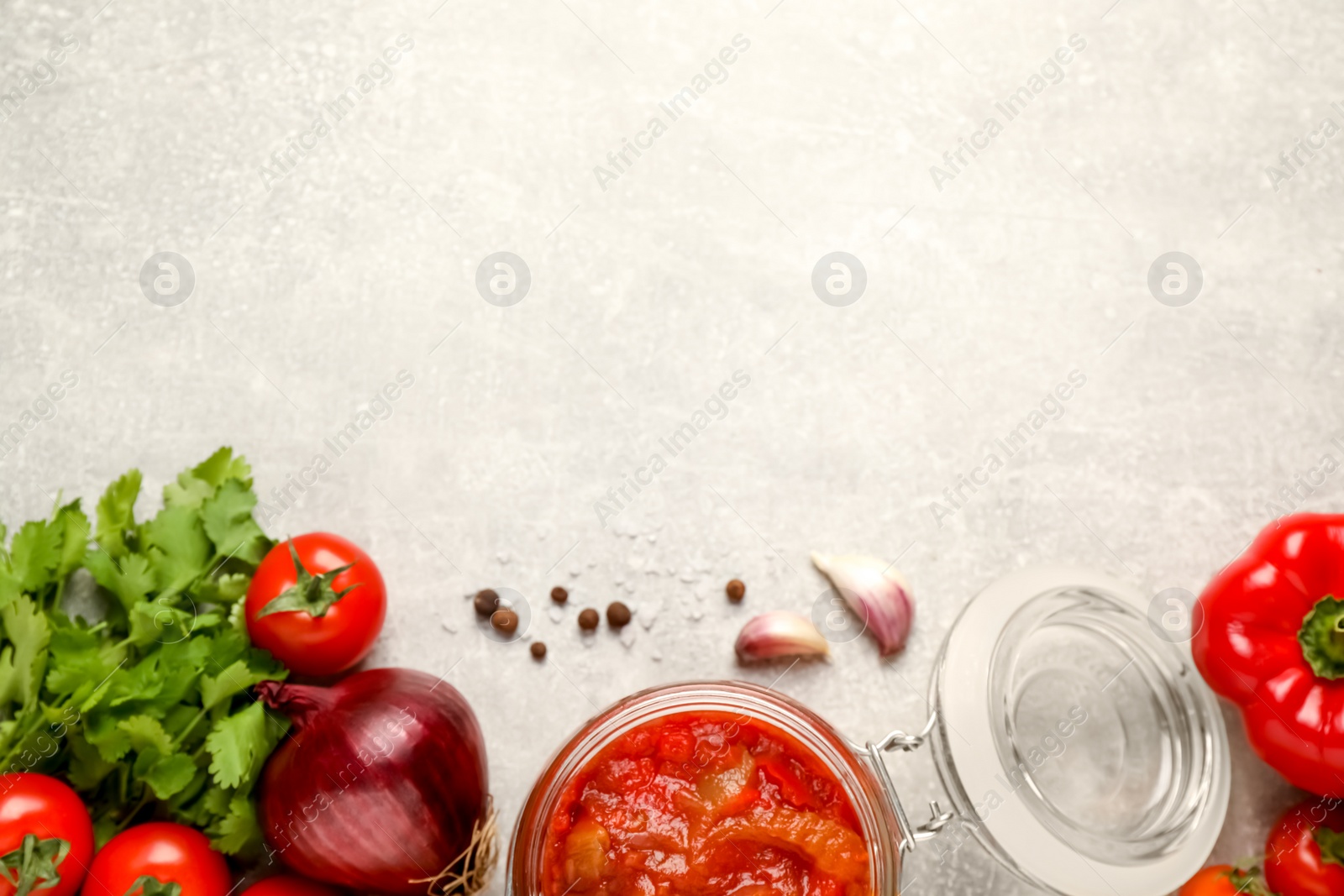 Photo of Glass jar of delicious canned lecho and fresh ingredients on light grey table, flat lay. Space for text