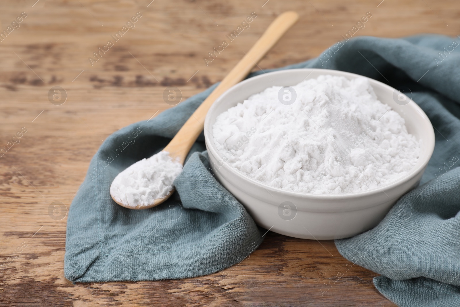 Photo of Bowl and spoon of natural starch on wooden table, closeup. Space for text