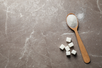 Photo of Spoon of white sugar on marble table, flat lay. Space for text