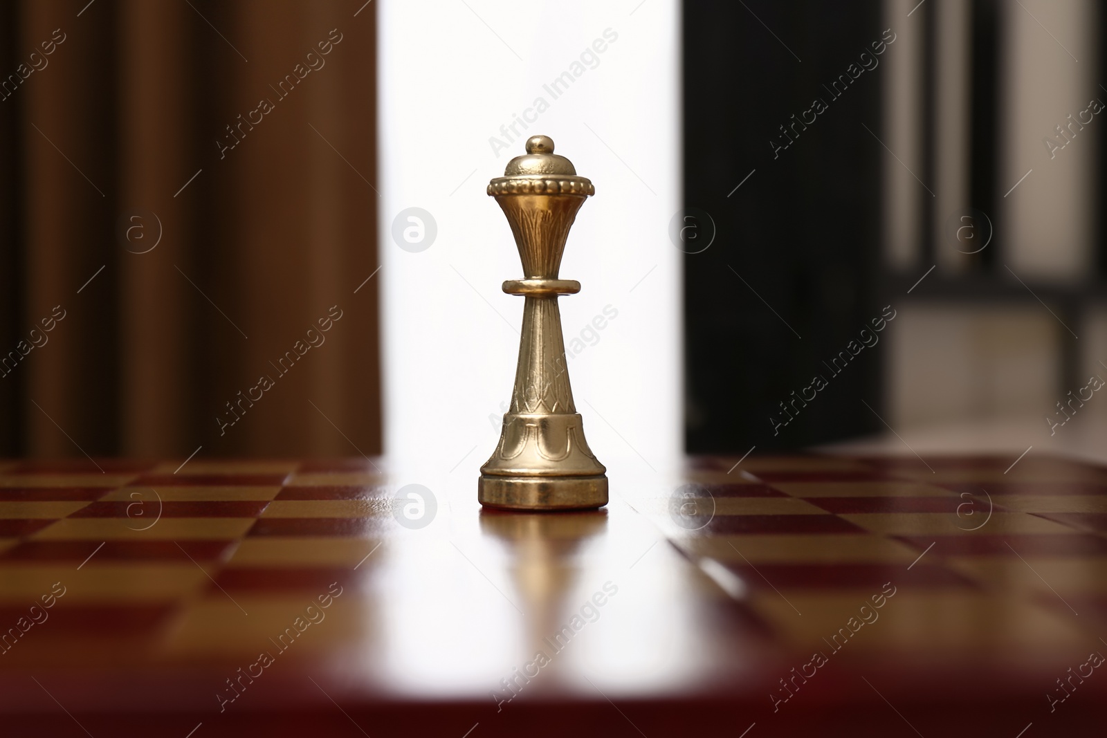 Photo of Golden Queen chess piece on board indoors