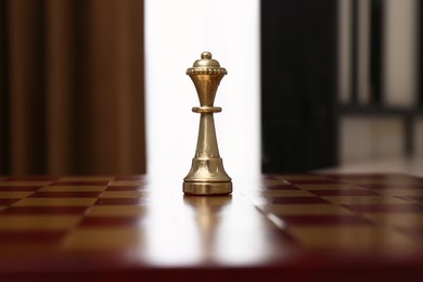 Photo of Golden Queen chess piece on board indoors