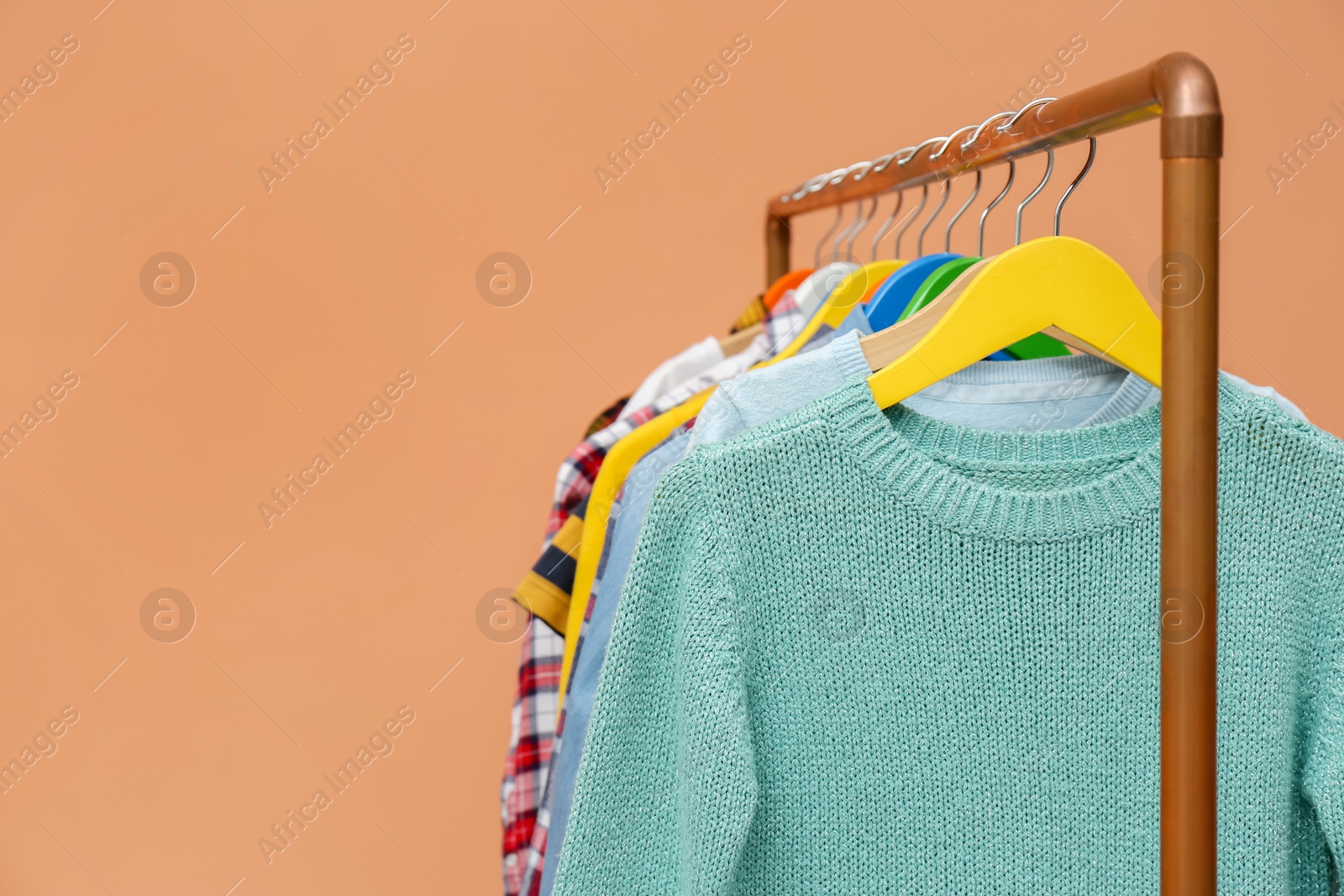Photo of Rack with stylish children clothes on beige background, closeup. Space for text
