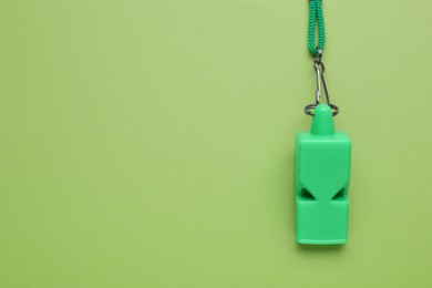 One color whistle with cord on light green background, top view. Space for text