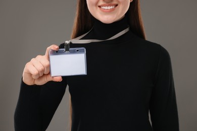 Woman with blank badge on grey background, closeup