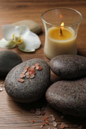 Photo of Beautiful composition with spa stones and burning candle on wooden table