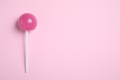 Photo of Stick with bright lollipop on pink background, top view. Space for text