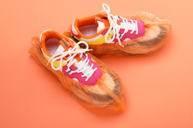 Photo of Women's sneakers in shoe covers on coral background, above view