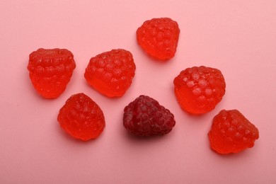 Delicious gummy candies and fresh raspberry on pink background