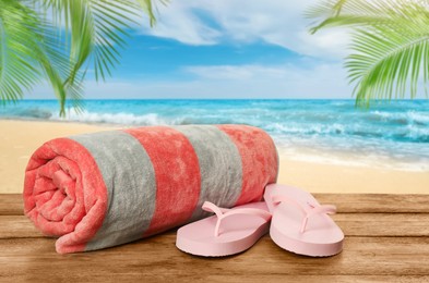 Image of Beach towel and flip flops on wooden surface near seashore