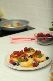 Photo of Delicious cottage cheese pancakes with fresh berries and mint on white countertop