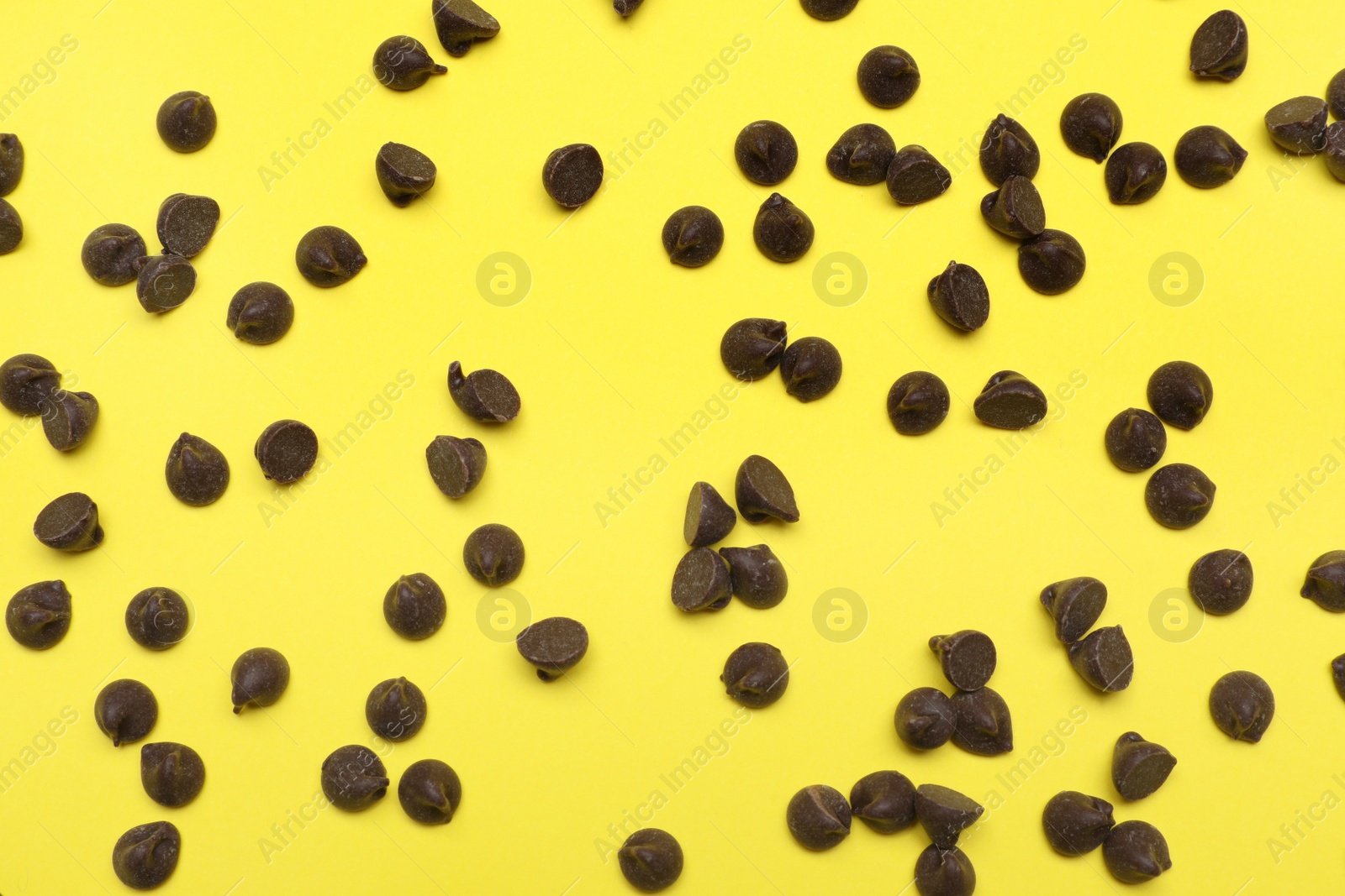 Photo of Delicious chocolate chips on yellow background, top view