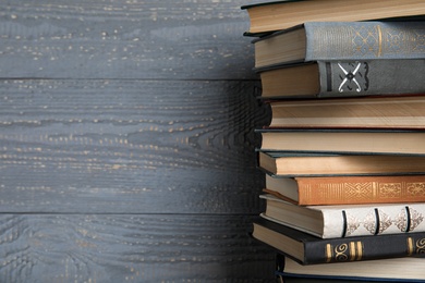 Stack of hardcover books on grey wooden background. Space for text