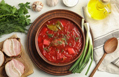 Photo of Stylish brown clay bowl with Ukrainian borsch served on white wooden table, flat lay