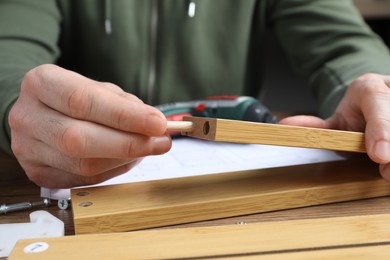 Photo of Man assembling wooden furniture at table, closeup