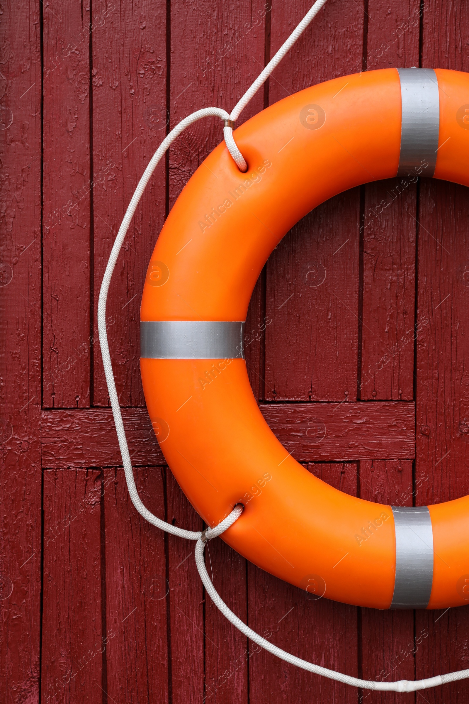 Photo of Orange life buoy hanging on red wooden wall