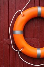 Photo of Orange life buoy hanging on red wooden wall