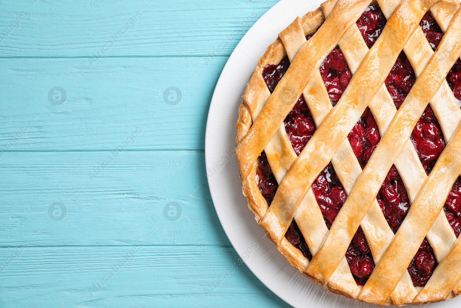 Photo of Delicious fresh cherry pie on light blue wooden table, top view. Space for text