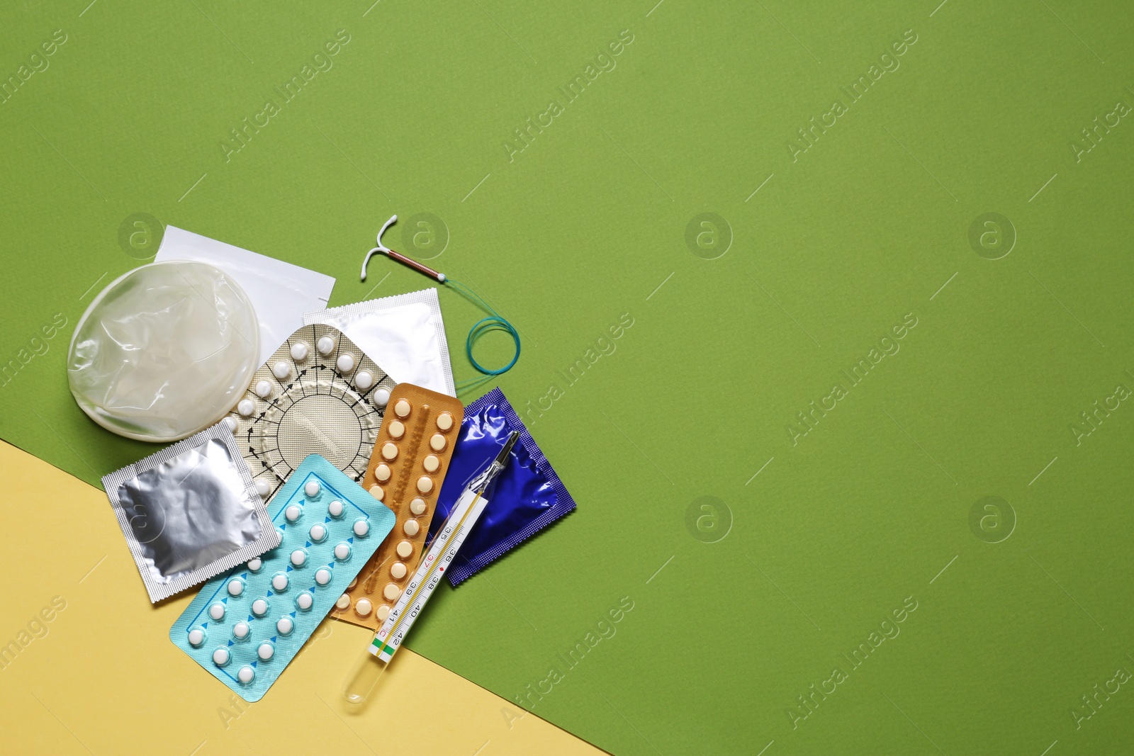 Photo of Contraceptive pills, condoms, intrauterine device and thermometer on color background, flat lay with space for text. Different birth control methods