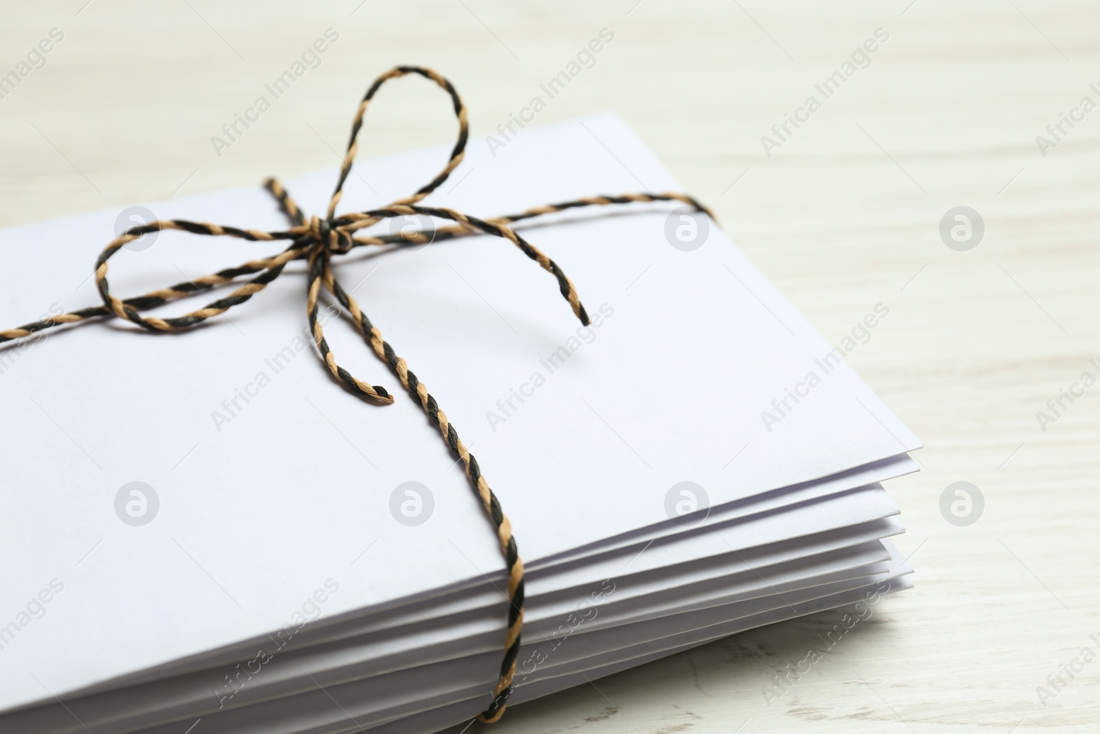 Photo of Stack of letters tied with string on white wooden table, closeup