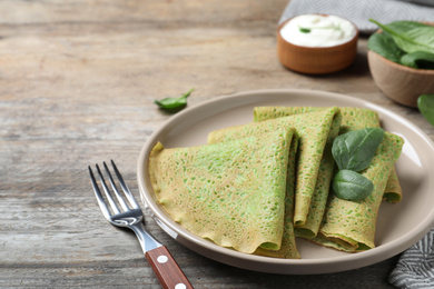 Photo of Delicious spinach crepes served on wooden table