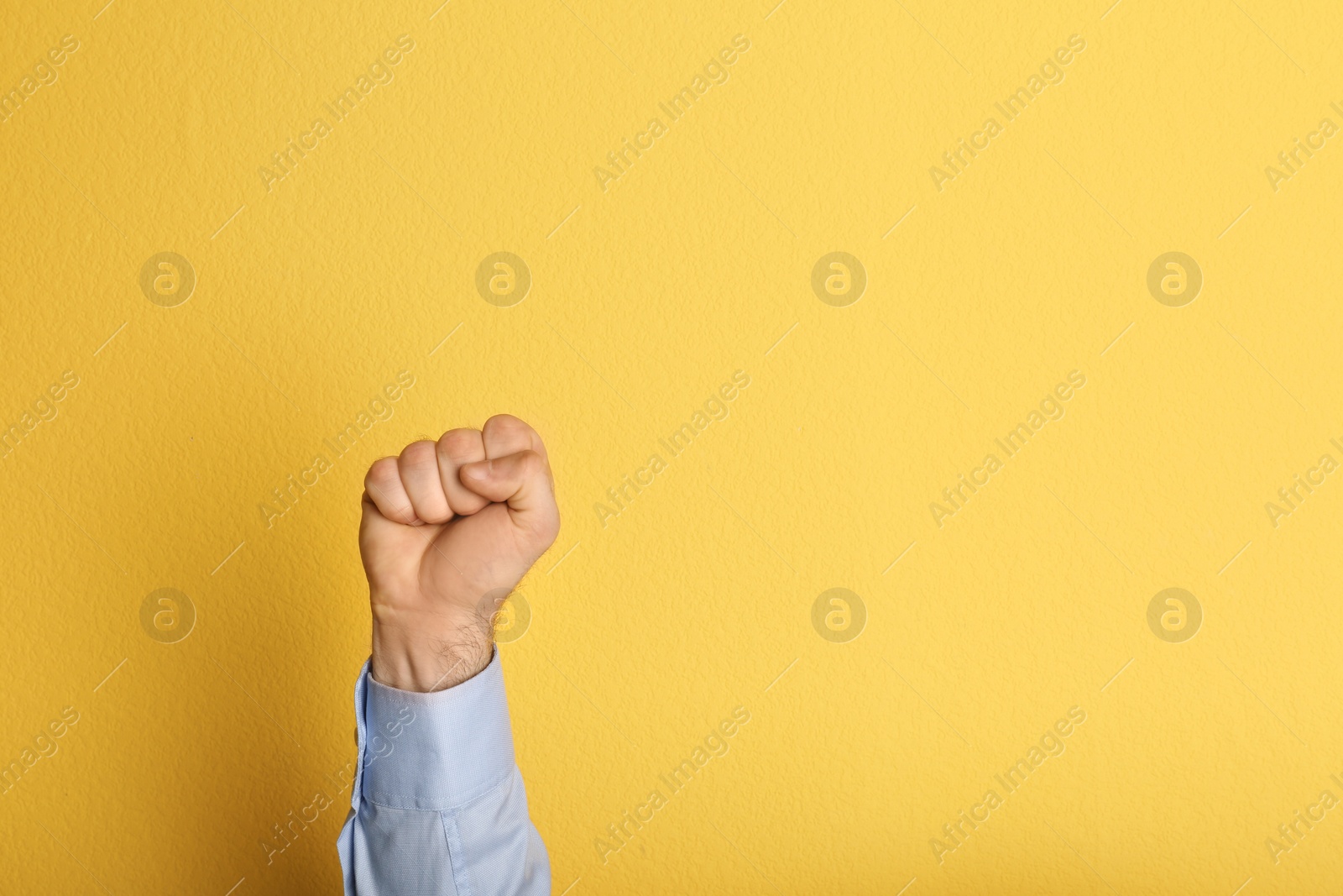 Photo of Young man showing clenched fist on color background. Space for text